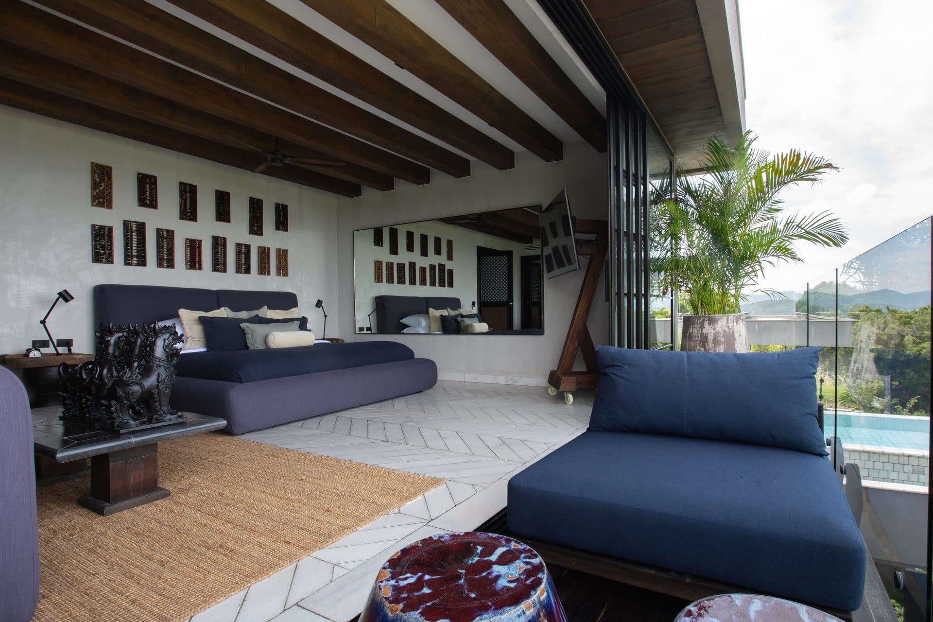 Master bedroom opening through full-height glass to the outside