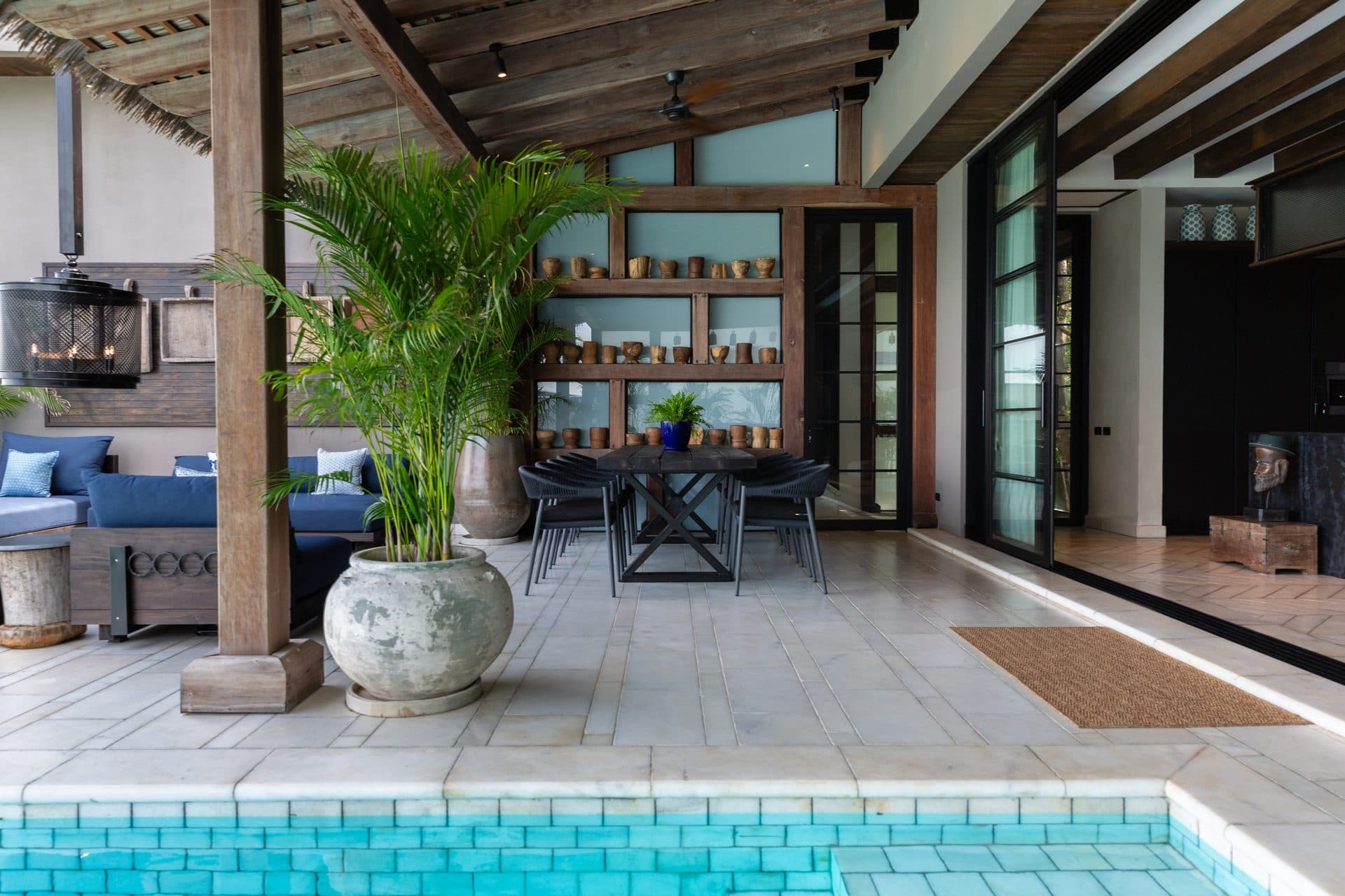 Pool deck with outdoor dining under a thatched pavilion